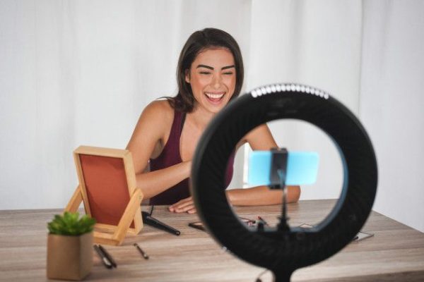 young-influencer-woman-creating-social-media-videos-with-smartphone-camera-while-putting-make-up_166273-280